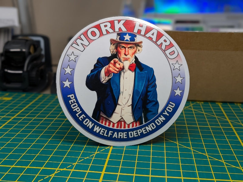 Sticker with Uncle Sam graphic and text 'Work Hard, People on Welfare Depend on You' on a cutting mat.