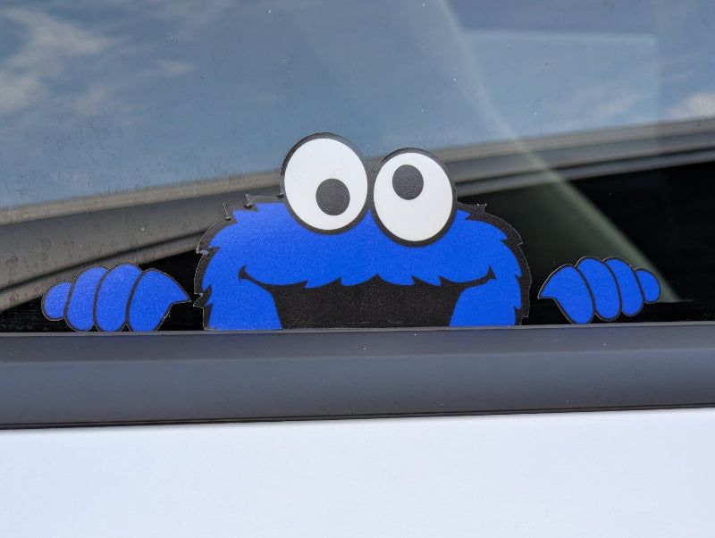 Blue creature with large eyes peeking out from a car window