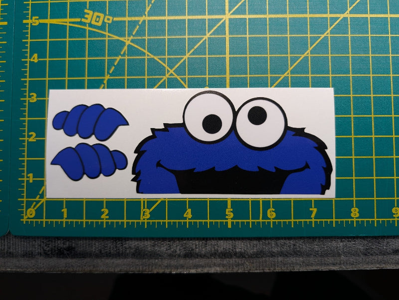 Cookie Monster face cutout on a green cutting mat with grid lines
