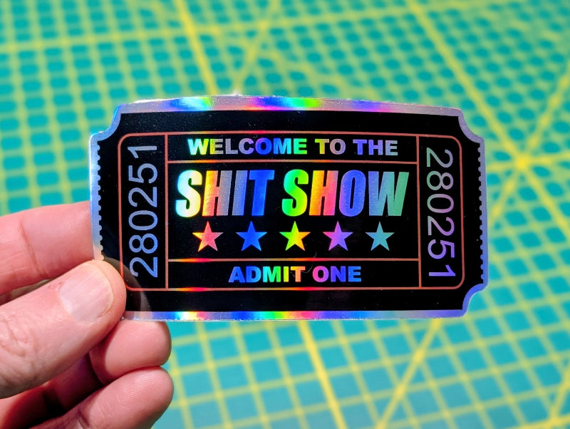 Holographic 'Welcome to the Shit Show' ticket decal on a clear water bottle."