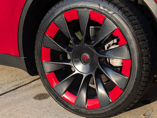 Close-up of a red Tesla Model Y featuring black 20-inch Induction rims upgraded with custom red vinyl wheel decals.