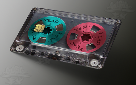 Close-up of a credit card skin featuring a realistic transparent cassette tape design with teal and pink reel-to-reel wheels and a gold EMV chip cutout.